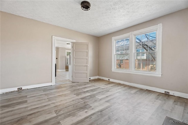 unfurnished room with a textured ceiling, wood finished floors, and baseboards