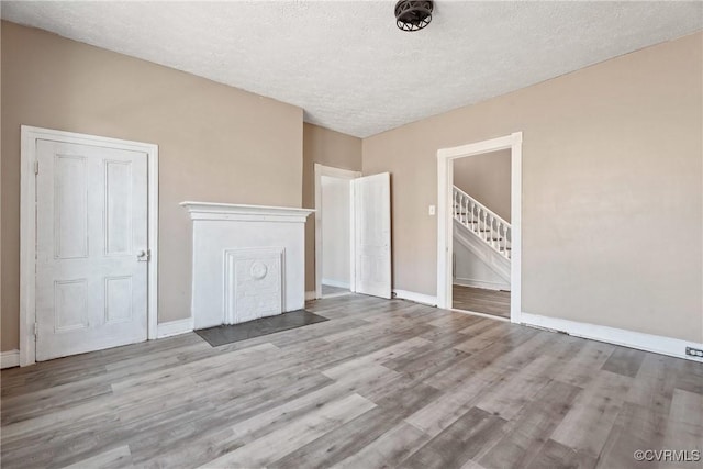 interior space featuring a textured ceiling, stairway, and wood finished floors