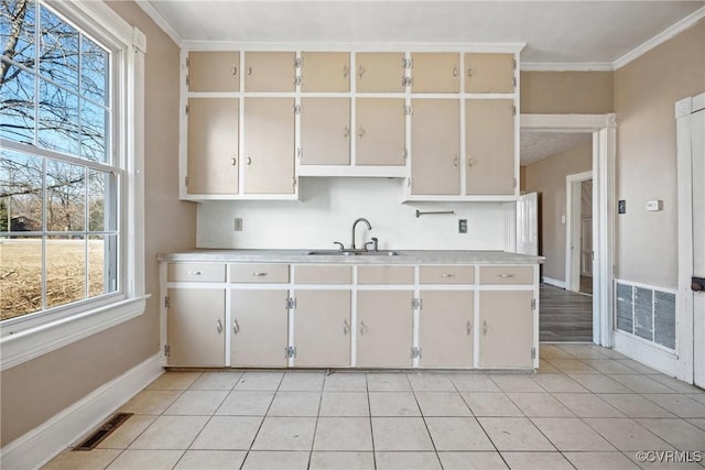 kitchen with light tile patterned floors, light countertops, a sink, and visible vents