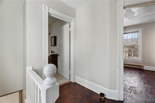 hall with a baseboard radiator, wood finished floors, and baseboards