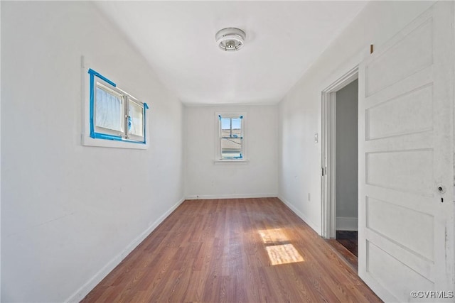 spare room featuring baseboards and wood finished floors