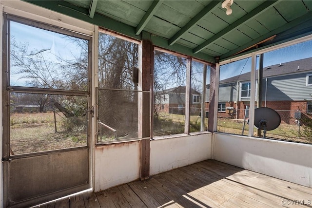 unfurnished sunroom featuring lofted ceiling with beams