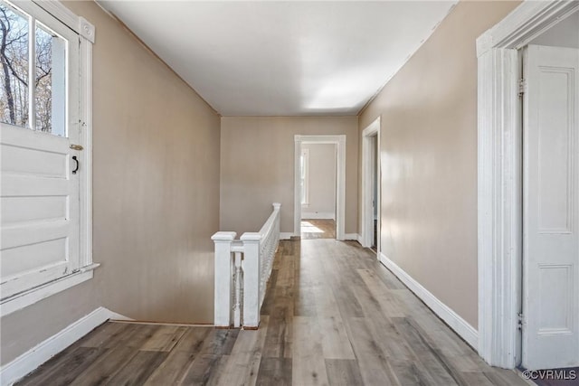 hall featuring baseboards, an upstairs landing, and wood finished floors