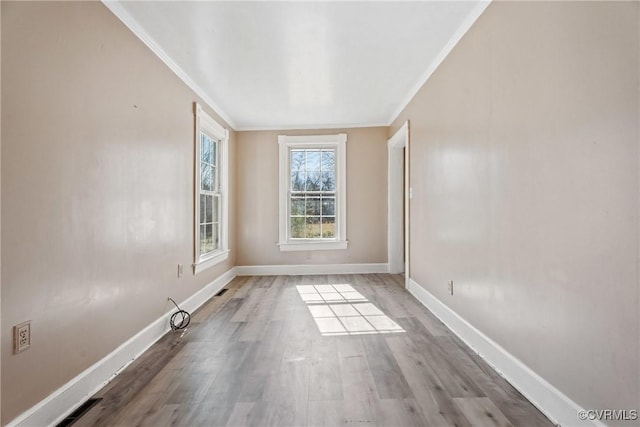 spare room featuring crown molding, wood finished floors, and baseboards