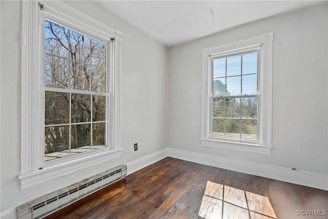 spare room with dark wood-style flooring, a baseboard radiator, and baseboards