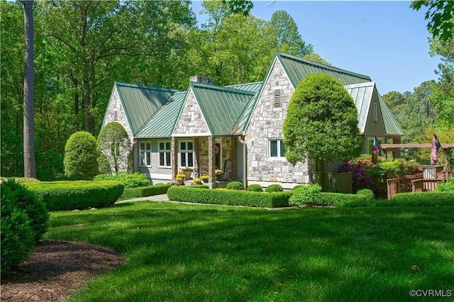 view of front facade with a chimney, a standing seam roof, metal roof, stone siding, and a front lawn