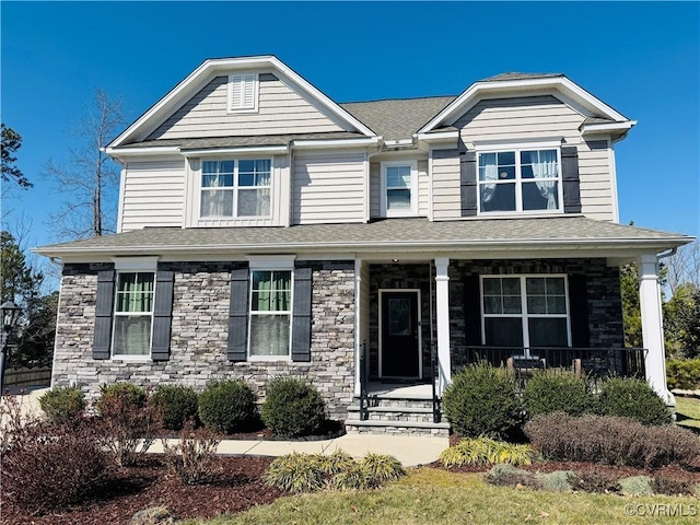 craftsman house featuring covered porch, stone siding, and roof with shingles