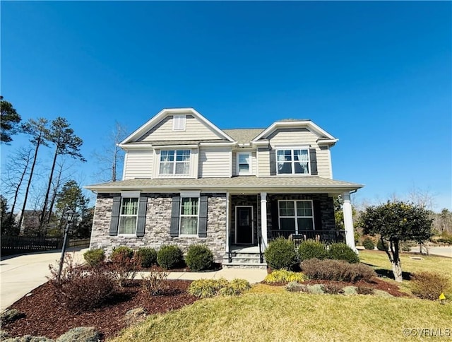 craftsman-style home featuring stone siding, a porch, concrete driveway, and a front yard