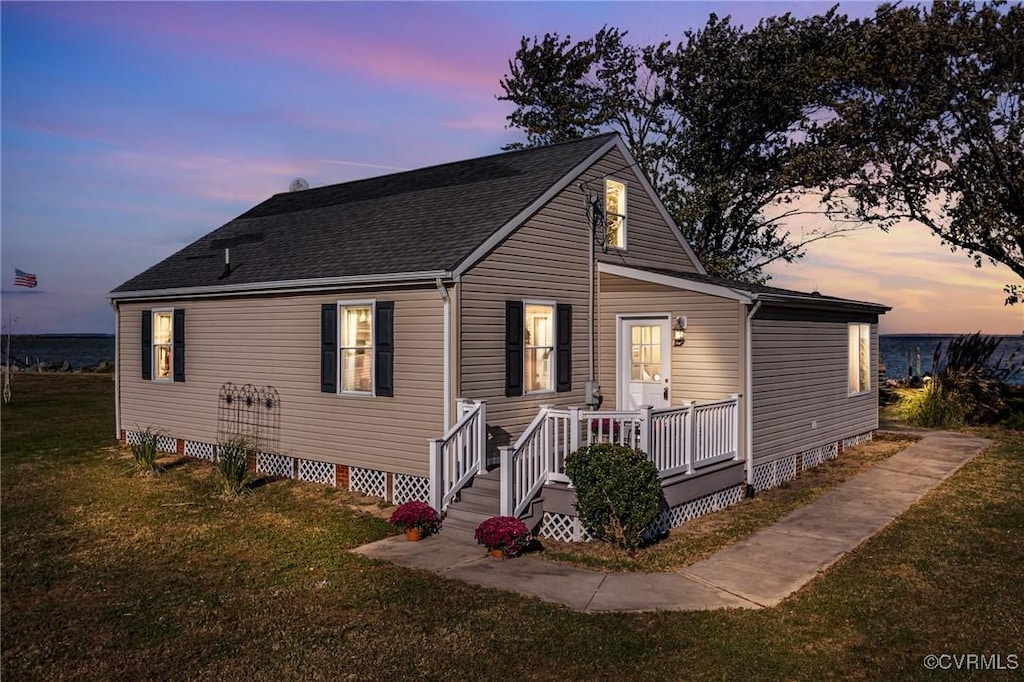 view of front facade with roof with shingles, crawl space, and a lawn