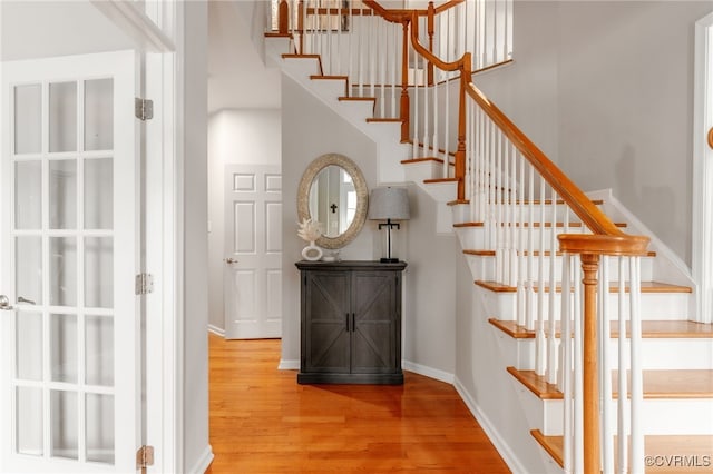 staircase with a high ceiling, baseboards, and wood finished floors