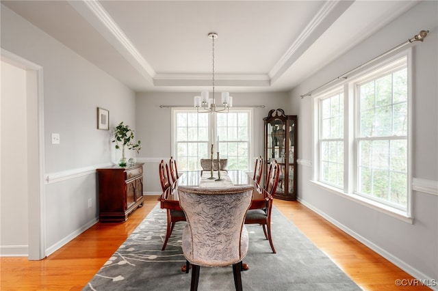 dining area featuring baseboards, ornamental molding, a tray ceiling, light wood-style floors, and a chandelier