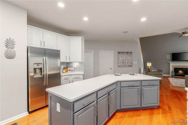 kitchen with white cabinets, open floor plan, gray cabinets, a center island, and stainless steel fridge