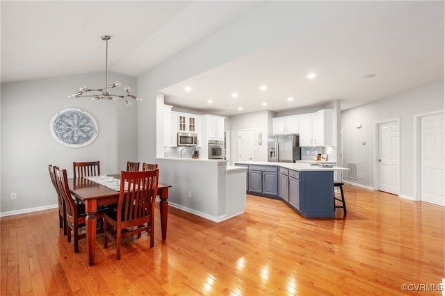 dining space featuring lofted ceiling, baseboards, light wood finished floors, and recessed lighting