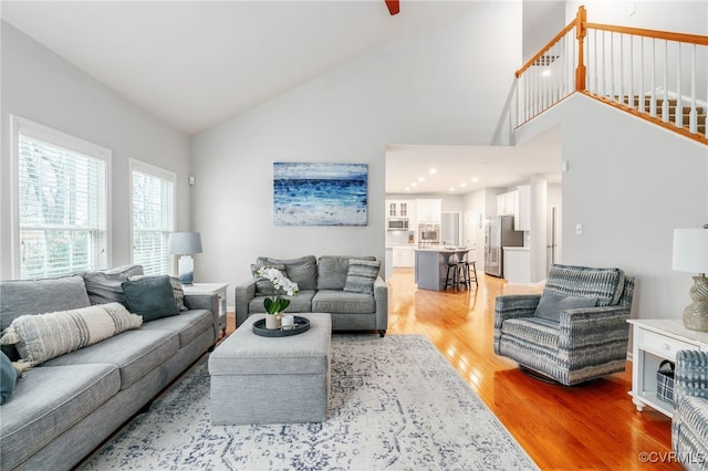 living area featuring high vaulted ceiling and light wood-type flooring