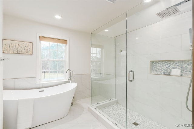 full bath with a stall shower, recessed lighting, tile walls, and a soaking tub