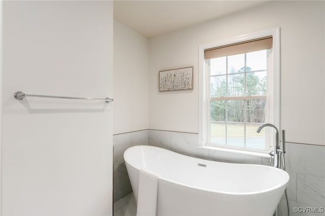 full bathroom featuring a wainscoted wall, tile walls, and a freestanding bath