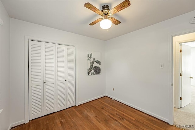 unfurnished bedroom with ceiling fan, a closet, wood finished floors, and baseboards