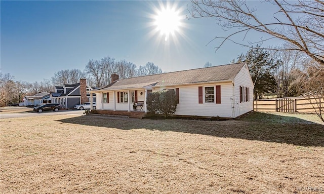 ranch-style house featuring a chimney, fence, and a front yard