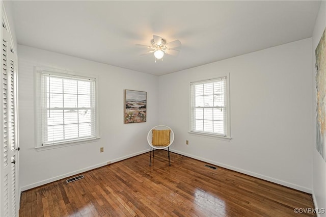 unfurnished room featuring a ceiling fan, baseboards, visible vents, and wood finished floors