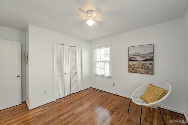 bedroom with wood finished floors, a ceiling fan, visible vents, baseboards, and a closet