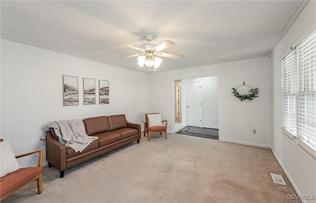 carpeted living room with visible vents, crown molding, baseboards, and ceiling fan