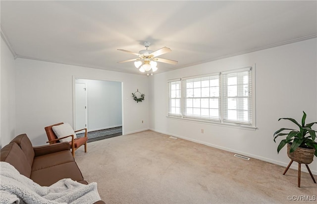 living area with baseboards, carpet floors, ceiling fan, and crown molding