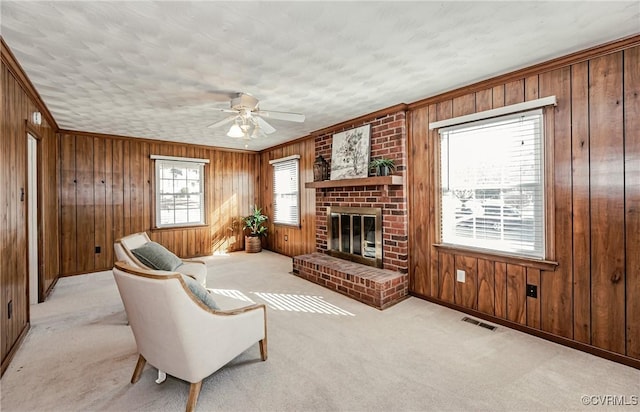 living room with a brick fireplace, wooden walls, visible vents, and carpet flooring