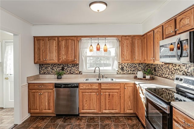 kitchen featuring light countertops, appliances with stainless steel finishes, a sink, and brown cabinets