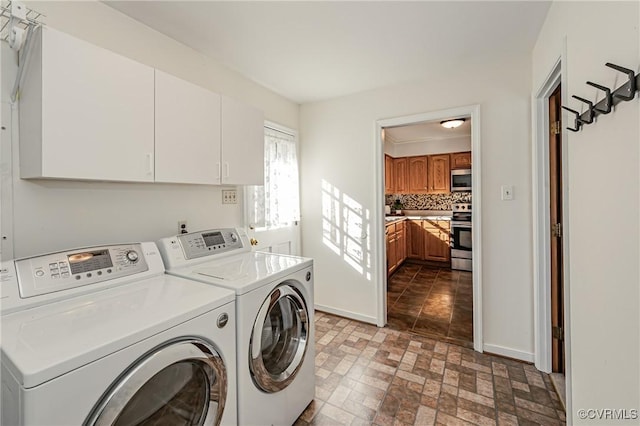 laundry room with washer and clothes dryer, brick floor, cabinet space, and baseboards