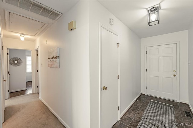 hall with attic access, visible vents, and baseboards