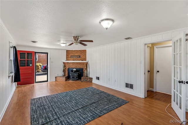 unfurnished living room featuring a wood stove, visible vents, and wood finished floors