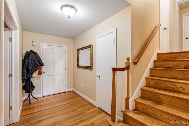 foyer with light wood-type flooring, stairway, and baseboards