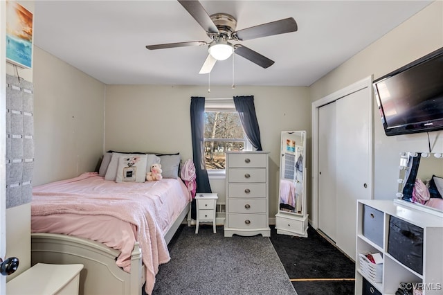 bedroom with ceiling fan, dark colored carpet, and a closet