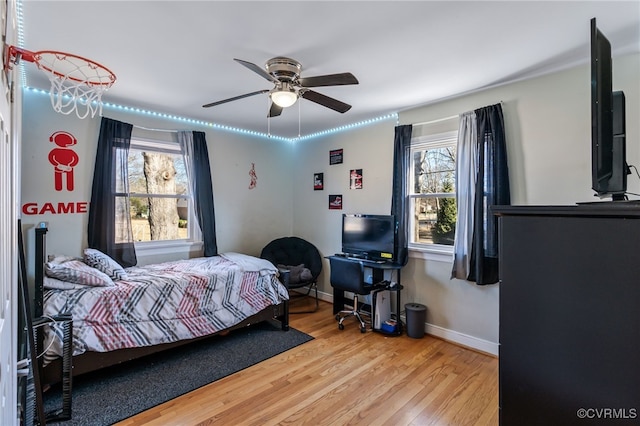 bedroom with ceiling fan, wood finished floors, and baseboards