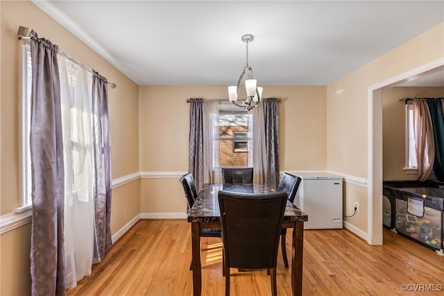 dining room with a healthy amount of sunlight, a notable chandelier, and light wood finished floors