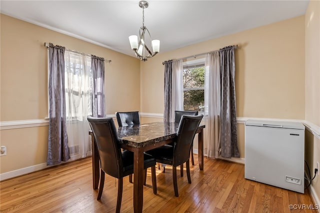 dining area with baseboards, light wood-type flooring, and a notable chandelier