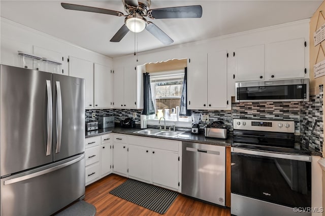 kitchen with stainless steel appliances, dark countertops, tasteful backsplash, white cabinetry, and a sink