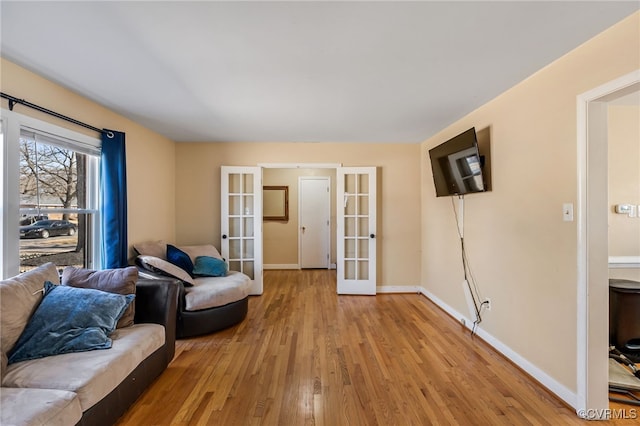 living area featuring light wood-style floors, french doors, and baseboards