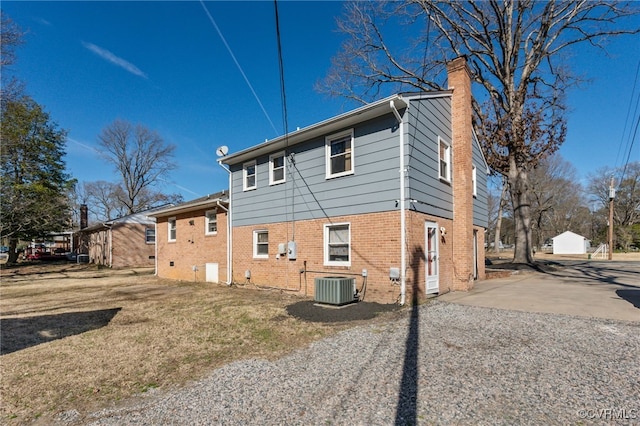 view of home's exterior with a yard, central AC, brick siding, and a chimney