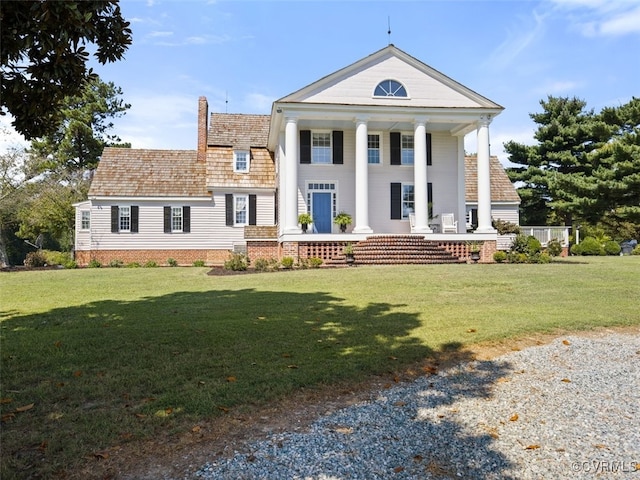 view of front facade featuring a porch, a front yard, and a chimney