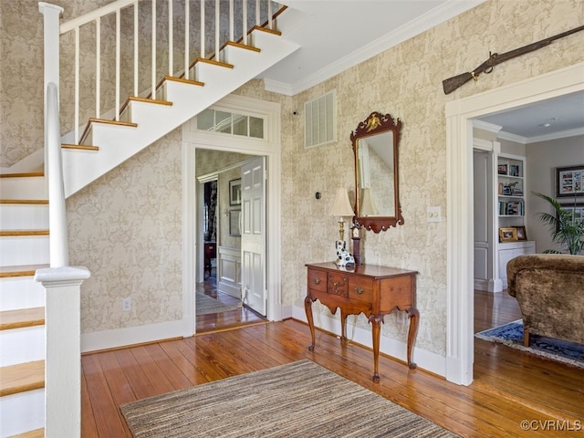 interior space featuring visible vents, baseboards, wallpapered walls, wood-type flooring, and crown molding