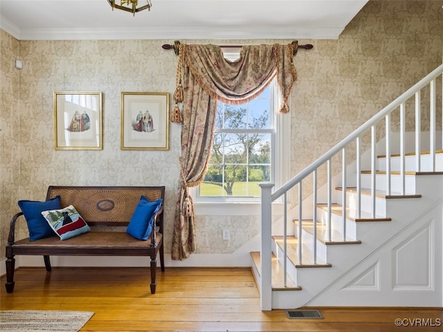 living area with hardwood / wood-style flooring, crown molding, and wallpapered walls