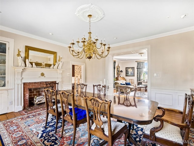 dining room with a wainscoted wall, crown molding, a brick fireplace, and wood finished floors