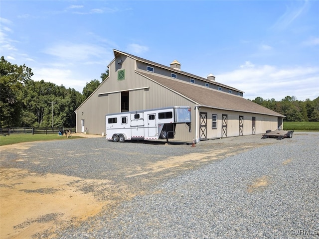 view of side of property with a barn, a detached garage, fence, and an outdoor structure