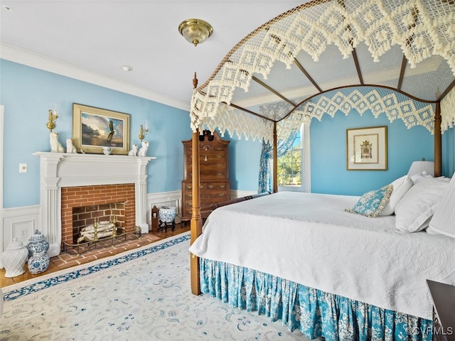 bedroom featuring wainscoting, a fireplace, and crown molding