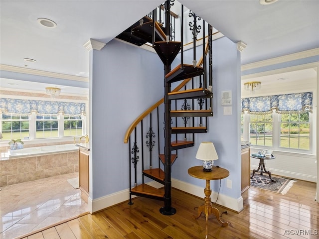 staircase featuring crown molding, plenty of natural light, baseboards, and hardwood / wood-style flooring