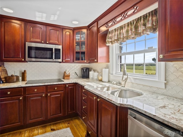 kitchen featuring a sink, light stone counters, stainless steel appliances, and dark brown cabinets