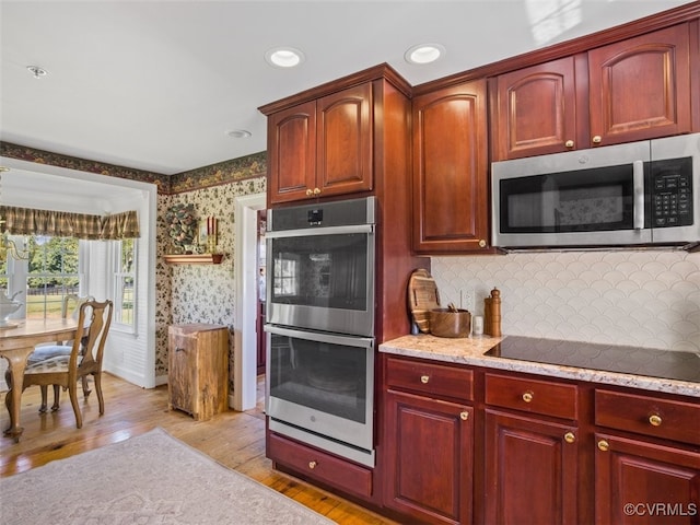 kitchen featuring stainless steel appliances, light wood finished floors, dark brown cabinets, and wallpapered walls