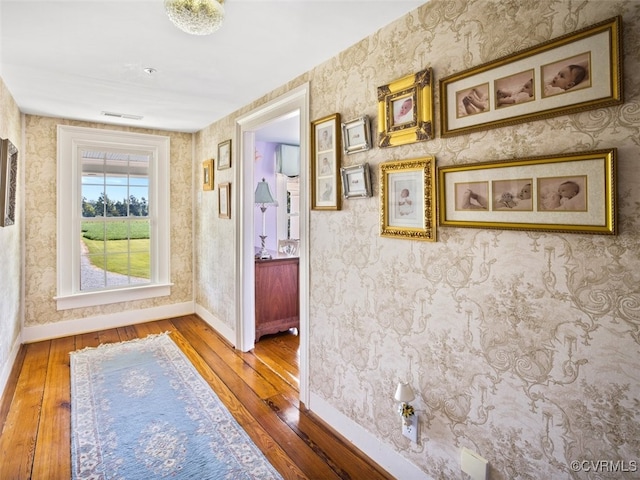 hall featuring hardwood / wood-style flooring, baseboards, and wallpapered walls