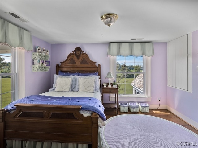 bedroom with wood finished floors, visible vents, and baseboards